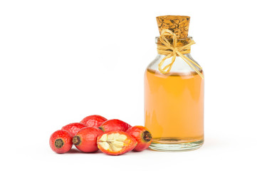 Glass bottle of rosehip seed essential oil with fresh rose hip fruits isolated on white background. Dogrose oil with fresh dog roses