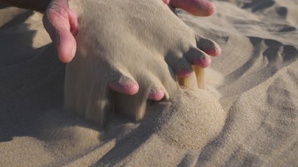 Sand in the hands. Close up view of sand running through a hands. Slow motion.