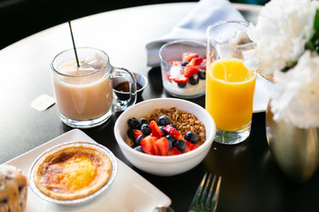 Breakfast with granola, yogurt, strawberries, blueberries, quiche, orange juice, and tea