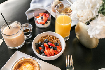 Breakfast with granola, yogurt, strawberries, blueberries, quiche, orange juice, and tea