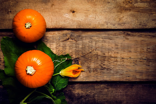 Autumn wooden background with pumpkins and leaves, top view, toned image with copy space