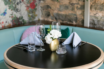 Nice table setting at restaurant with napkins, flowers, silverware, and wine glasses, trendy restaurant 