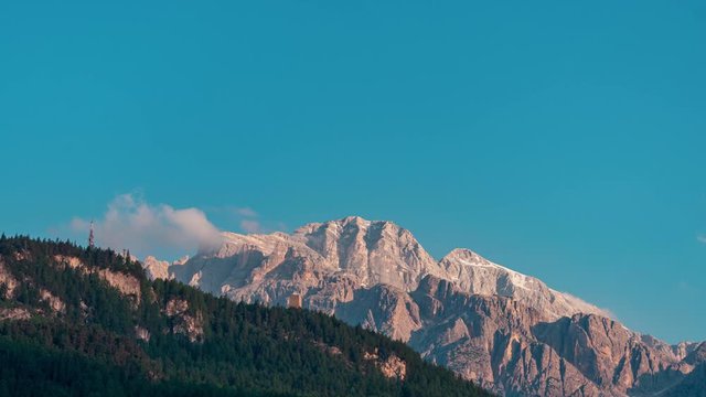 Early morning timelapse video of sunrise over the Italian Dolomite Alps. With beautiful sun rays and some fogy clouds over them. Shot during sunny summer day.