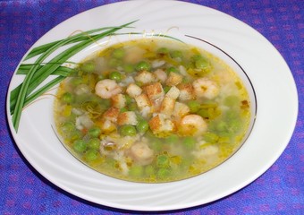 appetizing soup with salmon, shrimp, green peas and croutons in a beautiful plate on a blue backgrround