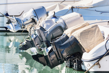 A row of outboard nautical engines mounted on fiberglass boats