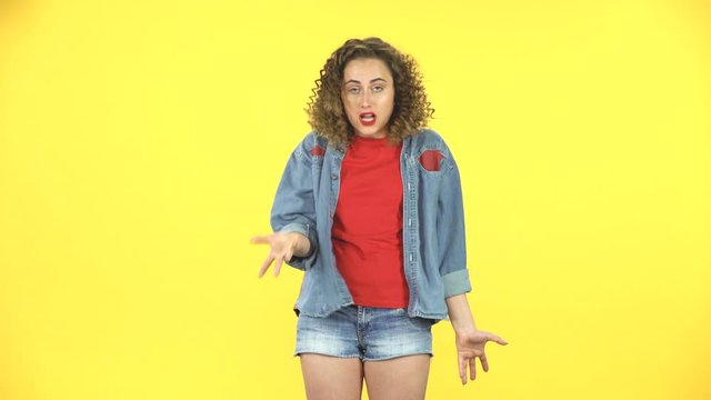 Indignant girl screaming, shows a hand sign at the head about abnormality, twists his finger at his temple