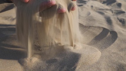 Sand in the hands of men. Close up view of sand running through a mans hands. Slow motion.