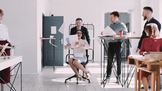 RED EPIC-W Happy young business woman celebrating success with office colleagues throwing paper in air slow motion.