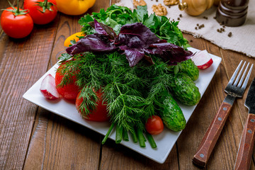 fresh vegetables and greens on a plate on wooden table