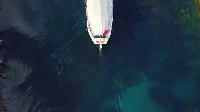 Aerial view of Akyaka river and reeds - A boats trip on the river and drone begin with top view after that follow the boat and tilt up with mountain background