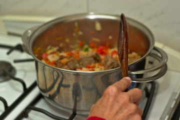 Preparing a tomato sauce, you are using a wooden spoon to move the preparation and fry lightly the ingredients.
