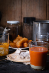 Traditional Thai hot tea with milk on the wood table there are Traditional Thai hot coffee, deep-fried doughstick (patongko), hot tea and soft-boiled egg plated around.
