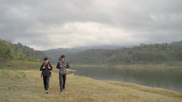 Two man hikers trekking near the lake at the morning