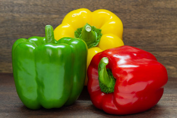 Red, green, yellow, sweet bell pepper on wooden background.