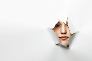 Woman looking out from a hole of torn paper