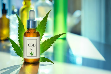 CBD OIL glass bottle, tincture and hemp leaf on a background of a medical laboratory. Concept of...