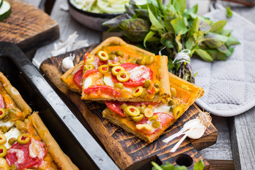 Homemade vegan pizza baked on tray. Square Italian vegetarian pizza pieces with olives, tomatoes. 