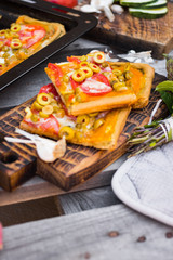 Homemade vegan pizza baked on tray. Square Italian vegetarian pizza pieces with olives, tomatoes. 