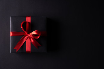 Top view of black christmas boxes with red ribbon on black background with copy space for text....