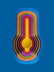 Measuring spoon set made of colorful plastic on a blue background, kitchen equipment. Group of steel measuring spoons closeup