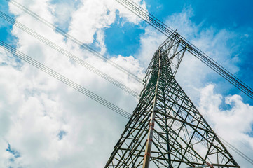 Electricity pylons with blue sky and white clouds. High voltage grid tower with wire cable at distribution station. High voltage electric tower and transmission lines.