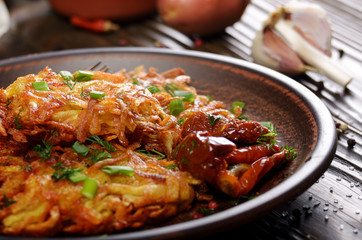 Closeup view at Homemade tasty potato pancakes in clay dish with sun-dried tomatoes