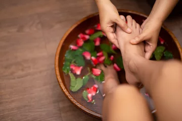 Afwasbaar Fotobehang Pedicure Top View  shot of a woman feet dipped in water with petals in a wooden bowl