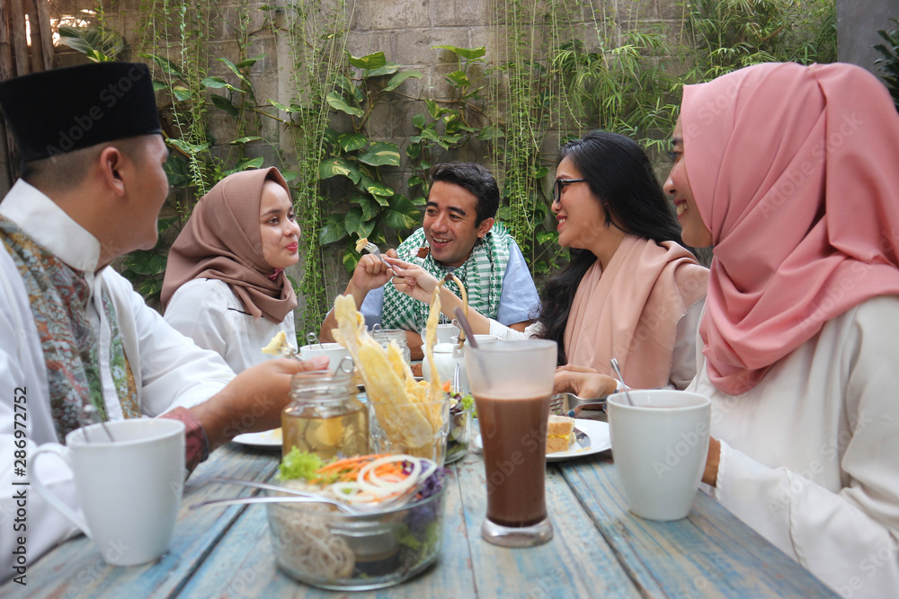 Wall mural group of happy young muslim having dinner outdoor during ramadan celebration