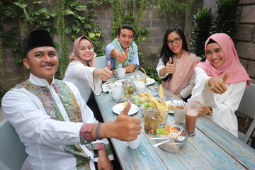 group of happy young muslim having dinner outdoor givung thumb up to camera