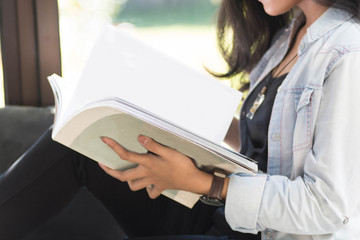 beautiful Asian women with glasses reading books while shiting by the window comfortably on a sunny...