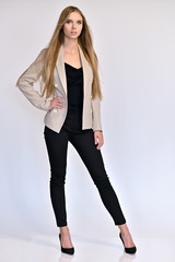 Vertical portrait of a pretty beautiful girl, a happy young woman manager in a jacket and black pants on a white background in studio. Smiling, showing emotions. - 286975176