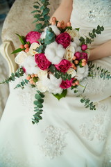 wedding bouquet of roses and cotton in the hands of the bride