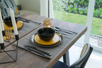 dining table with black and yellow plate setting in modern home.