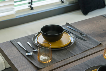 dining table with black and yellow plate setting in modern home.
