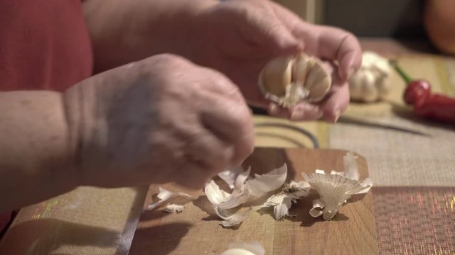 Elderly woman peeling garlic in the kitchen.