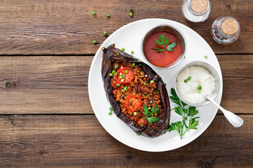 Karniyarik - Stuffed Eggplants, Aubergines with minced meat and vegetables baked with tomato sauce served on a plate.