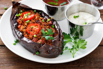 Karniyarik - Stuffed Eggplants, Aubergines with minced meat and vegetables baked with tomato sauce served on a plate.