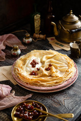 Homemade stack of thin crepes with sour cream and red jam on vintage pink plates