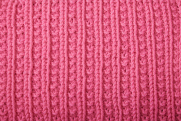 knitting sweaters, or a scarf with a red pattern, thin knitting needles on a white wooden background. Close-up. Copy space.
