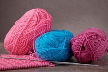 knitting sweaters, or a scarf with a red pattern, thin knitting needles on a white wooden background. Close-up. Copy space.