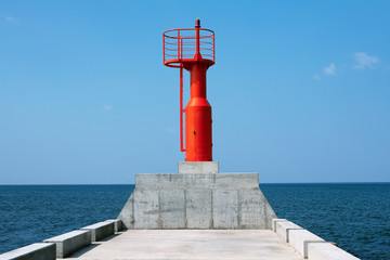 Fototapeta na wymiar Red lighthouse on a breakwater in Baltic sea, the Pavilosta, Latvia