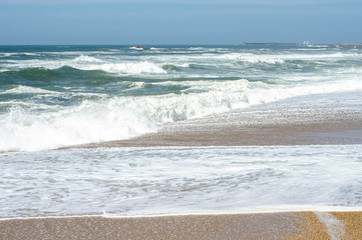 Ocean waves with foam on a shore of sand beach