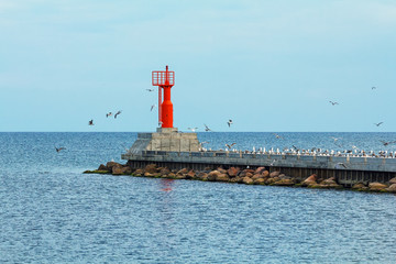 Red lighthouse on a breakwater in Baltic sea, the Pavilosta, Latvia