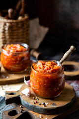 two glass jars with home made red vegetable caviar, ratatouille, ragout on wooden brown boards