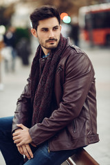 Thoughtful young man sitting on an urban bench.