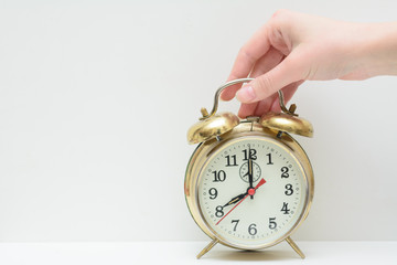 Female hand holds a vintage alarm clock. The concept is to wake up to work. Time to work