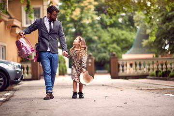 father and child holding hands going to school.