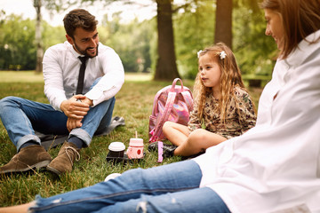 daughter with their parent sitting and resting at park..