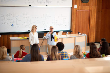professor helping student in class in university engaged in education..