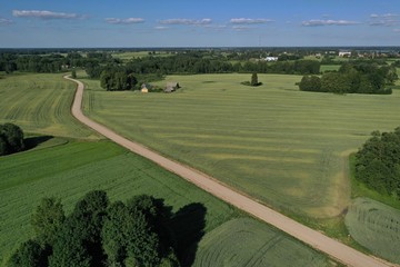 Aerial view of gravel road on farmland fields in summer